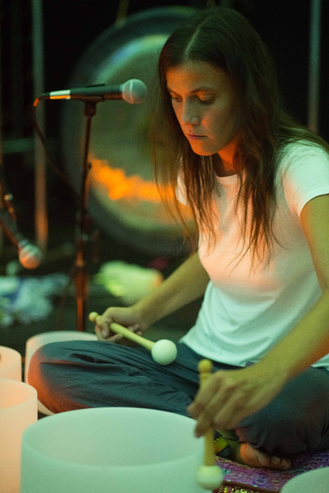Julia playing crystal bowls bathed in blue stage light